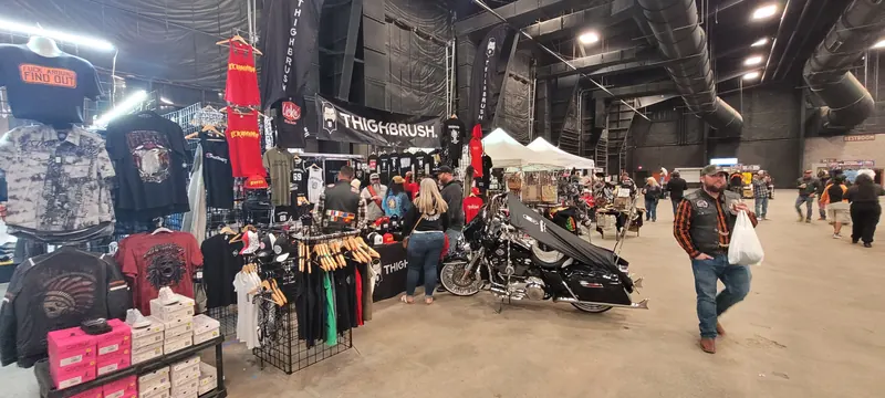 Indoor vendor hall with riding apparel and a bagger on display at Arizona Bike Week 2024
